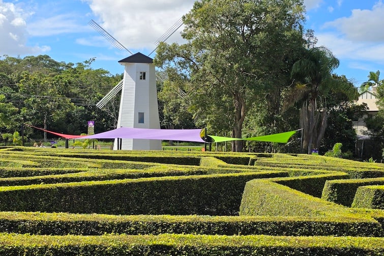 A white windmill and hedge maze at Amaze World.