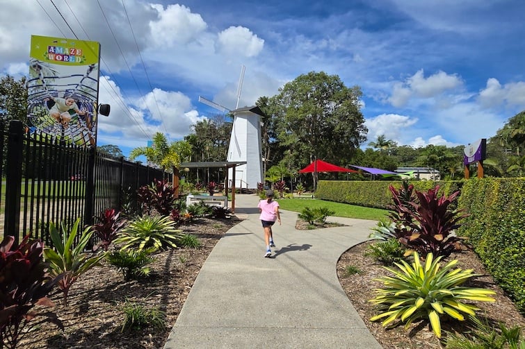 A girl on a pathway leading toward large white windmill at Amaze World.