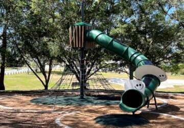 Green tunnel slide with smiley faces on the outside at Barbaralla Park.