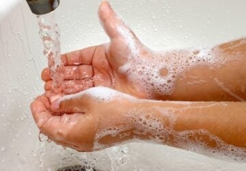 Child washing hands with soap under running water