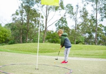 Victoria Park child standing on putting green about to putt.