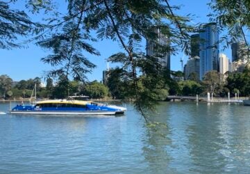 Brisbane River CityCat travelling down Brisbane River with city buildings in the background.