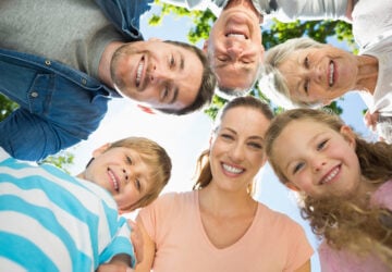 Portrait of extended family forming huddle in the park.
