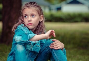 a homeless child sitting under tree