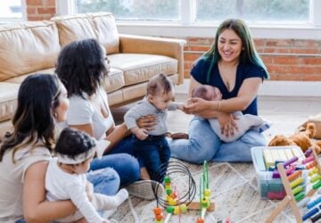 A group of ladies with babies and toddlers sitting on the floor.