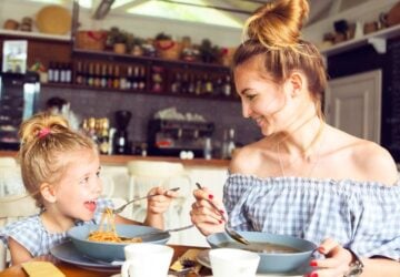 A girl and lady eating and smiling.
