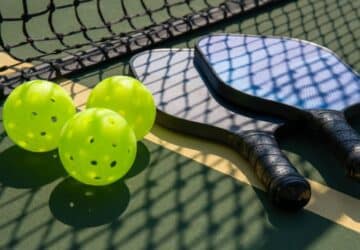 Two pickleball paddles and three pickleballs.