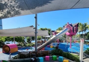 Colourful playground with large metal tunnel slide at Riverside Green playground.