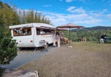 The Curious Caravan with blue skies and an umbrella.