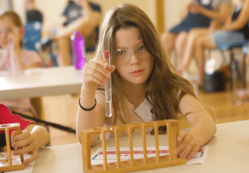 Atomic School child wearing goggles test tube science experiment.