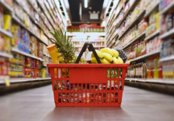 groceries in a red basket sitting in the middle of a supermarket