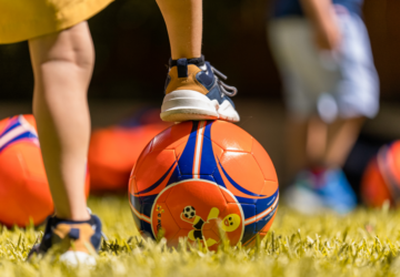 Ginger Sport child with foot on soccer ball.