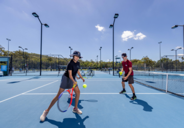 Griffith Sport child on tennis court with coach.